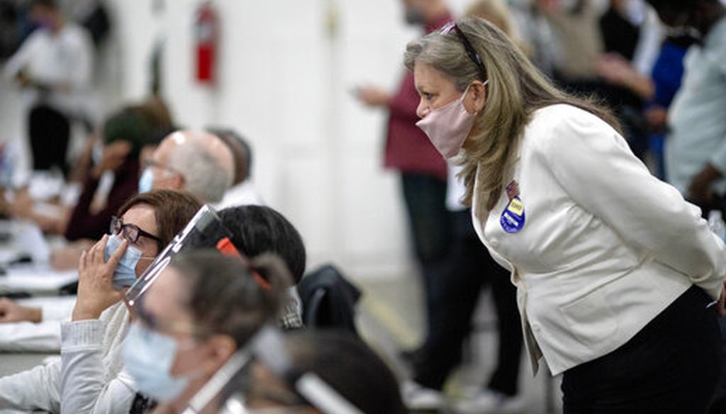 A Republican election challenger, right, watches over election inspectors examining ballots as votes are counted into the early morning hours Wednesday, Nov. 4, 2020, at the central counting site in Detroit. (AP)